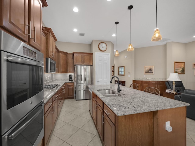 kitchen with stainless steel appliances, an island with sink, hanging light fixtures, light tile patterned floors, and sink