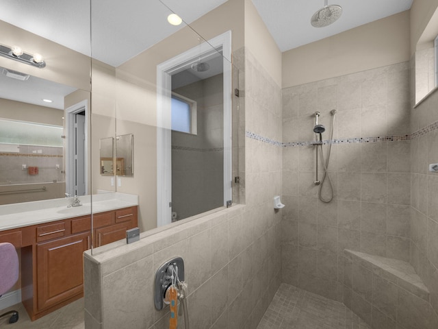 bathroom with tiled shower and vanity