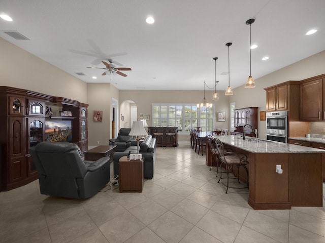 living room featuring sink, ceiling fan with notable chandelier, and light tile patterned floors