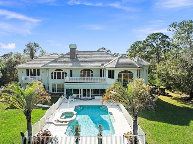 rear view of house featuring a yard, a balcony, a patio, and a pool with hot tub