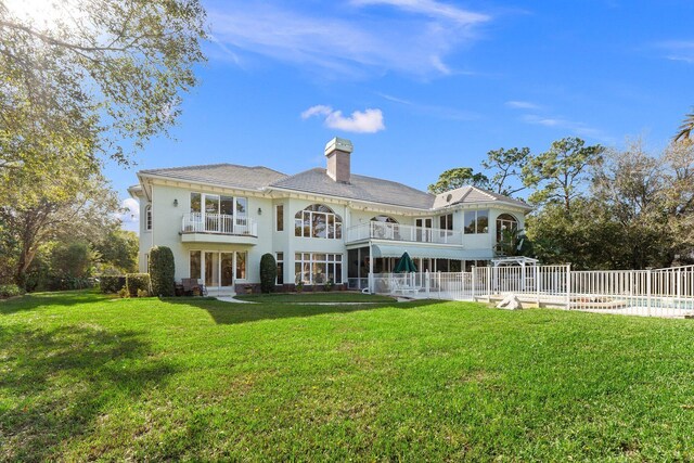 back of house with a yard, a balcony, and a swimming pool