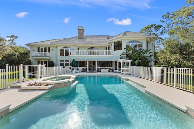 back of house featuring a pool with hot tub, a balcony, and a patio