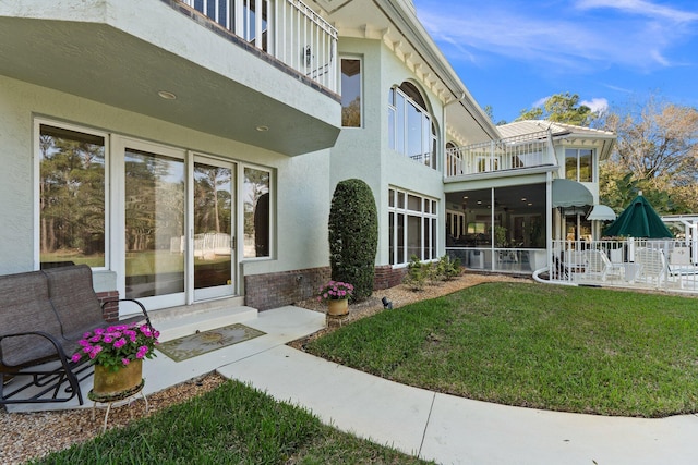 back of house featuring a lawn and a balcony