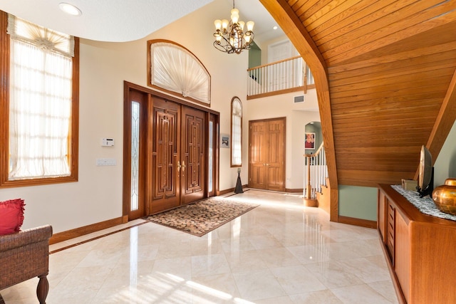 foyer entrance featuring a chandelier, a towering ceiling, and wooden ceiling