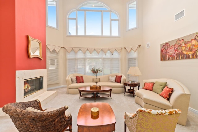 living room featuring a fireplace, carpet, a towering ceiling, and a wealth of natural light