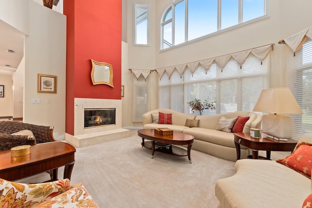 carpeted living room with a high end fireplace and a high ceiling