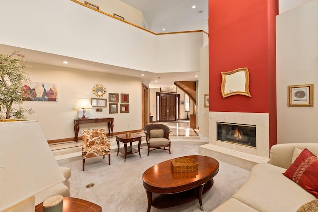 living room featuring a premium fireplace, carpet floors, and a high ceiling