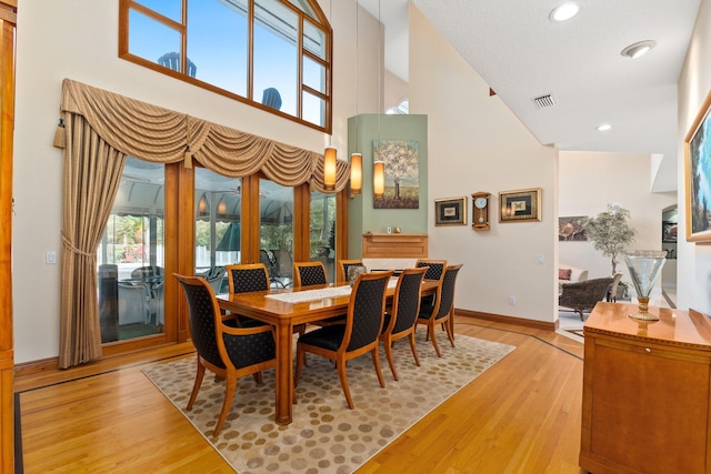 dining area with a high ceiling and light hardwood / wood-style flooring