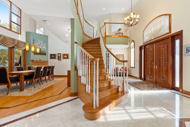 tiled foyer featuring a towering ceiling and an inviting chandelier