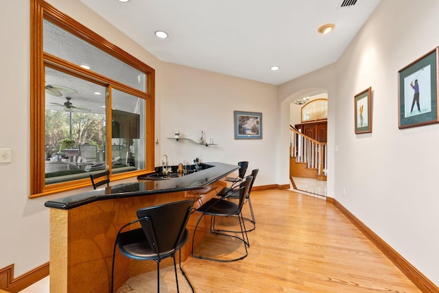 bar featuring ceiling fan, light hardwood / wood-style flooring, and sink