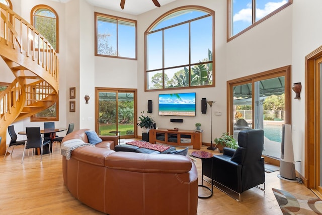 living room featuring ceiling fan, light hardwood / wood-style floors, and a high ceiling