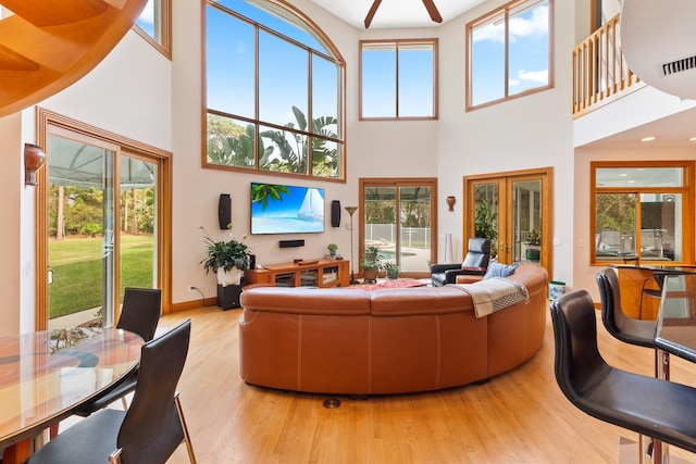 living room featuring french doors, plenty of natural light, a high ceiling, and light hardwood / wood-style flooring