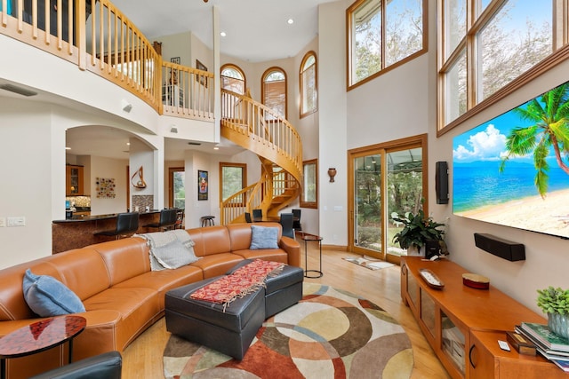 living room with plenty of natural light, light hardwood / wood-style flooring, and a high ceiling