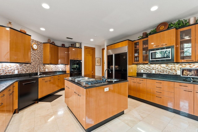 kitchen with decorative backsplash, sink, a center island with sink, and black appliances