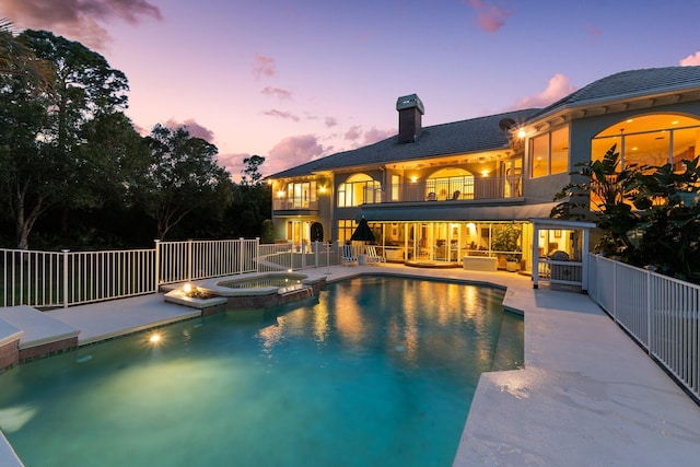 pool at dusk with an in ground hot tub and a patio