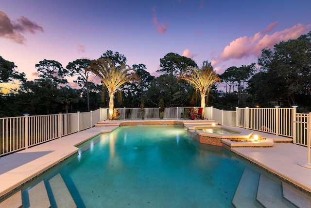 pool at dusk featuring an in ground hot tub and a patio area