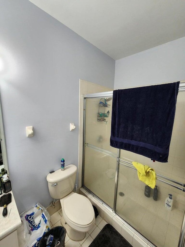 bathroom with tile patterned floors, a shower with door, and toilet