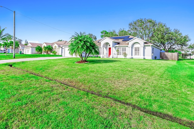 ranch-style home featuring solar panels, a front lawn, and a garage