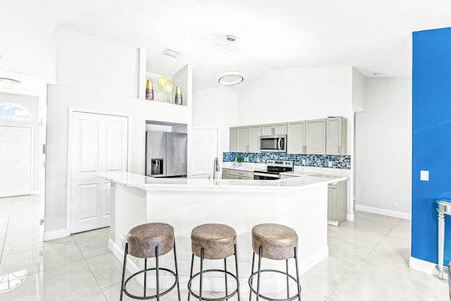 kitchen with an island with sink, tasteful backsplash, gray cabinets, appliances with stainless steel finishes, and sink