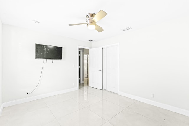 tiled empty room featuring ceiling fan