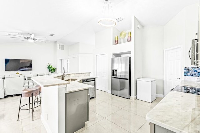 kitchen with white cabinets, a center island with sink, stainless steel appliances, sink, and decorative light fixtures