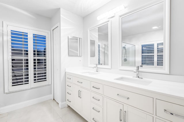 bathroom with a shower with door, vanity, and tile patterned floors