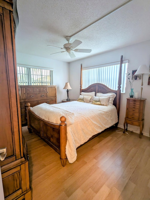 bedroom with multiple windows, ceiling fan, a textured ceiling, and light wood-type flooring