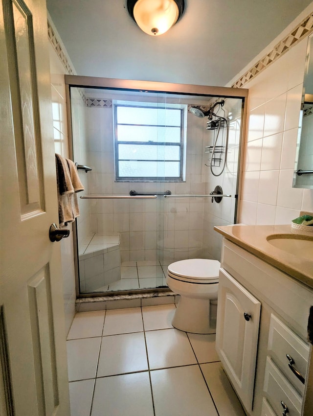 bathroom with vanity, toilet, a shower with shower door, and tile walls