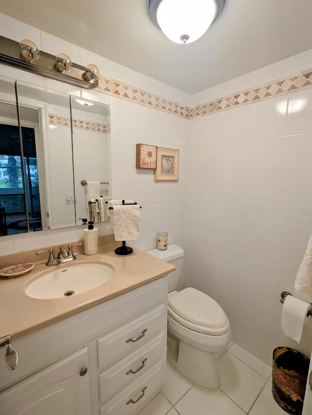 bathroom featuring vanity, toilet, tile patterned flooring, and tile walls