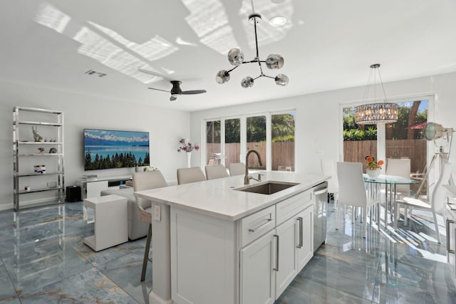 kitchen featuring a kitchen bar, a kitchen island with sink, sink, decorative light fixtures, and white cabinets