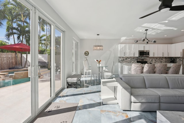 living room featuring ceiling fan with notable chandelier and sink