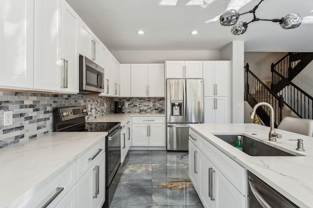 kitchen featuring sink, stainless steel appliances, light stone counters, backsplash, and white cabinets