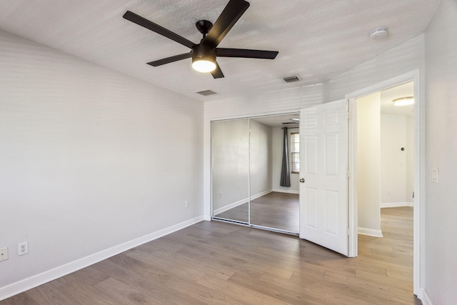 unfurnished bedroom with ceiling fan, light wood-type flooring, and a closet