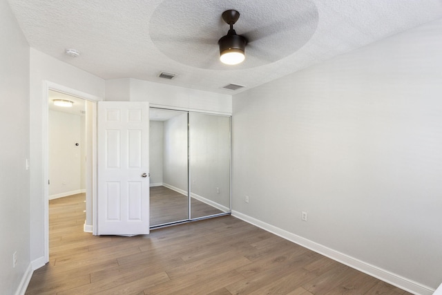 unfurnished bedroom featuring ceiling fan, a closet, hardwood / wood-style floors, and a textured ceiling