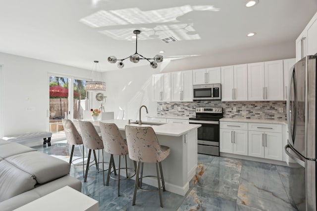 kitchen with white cabinets, sink, stainless steel appliances, and hanging light fixtures