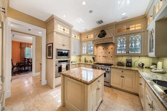 kitchen featuring a center island, stainless steel appliances, light stone counters, and tasteful backsplash