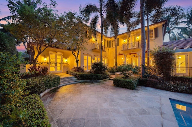 mediterranean / spanish-style home with a balcony, a patio, and french doors