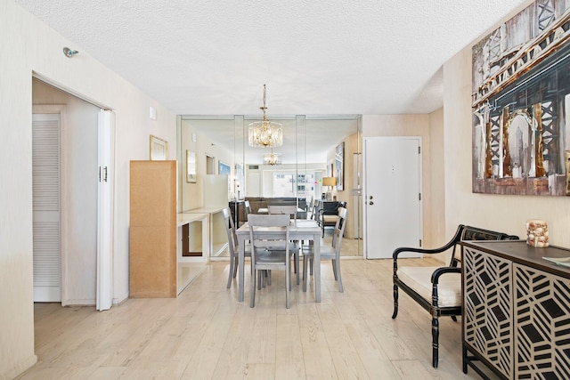 dining space with a chandelier, a textured ceiling, and light wood-type flooring