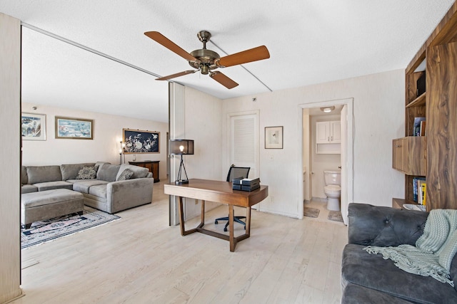 home office featuring ceiling fan, light hardwood / wood-style flooring, and a textured ceiling