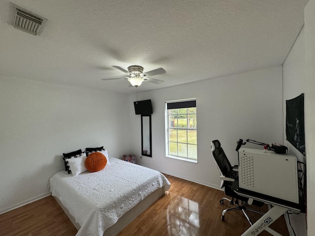 bedroom with hardwood / wood-style flooring, a textured ceiling, and ceiling fan