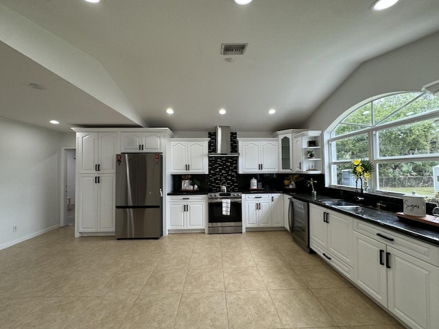 kitchen featuring white cabinetry, wall chimney range hood, vaulted ceiling, and appliances with stainless steel finishes