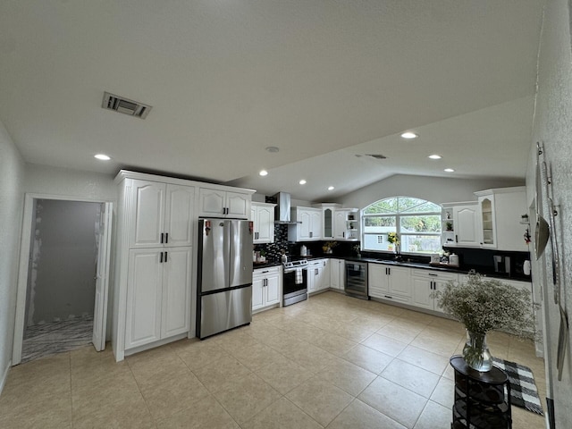 kitchen featuring stainless steel appliances, vaulted ceiling, beverage cooler, and white cabinetry