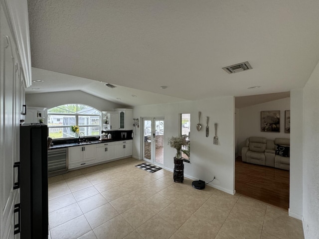 interior space featuring a wealth of natural light, vaulted ceiling, beverage cooler, and french doors