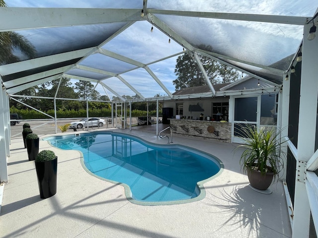 view of pool with a patio area and glass enclosure