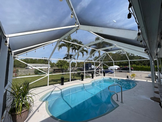 view of pool with a patio, glass enclosure, and a lawn