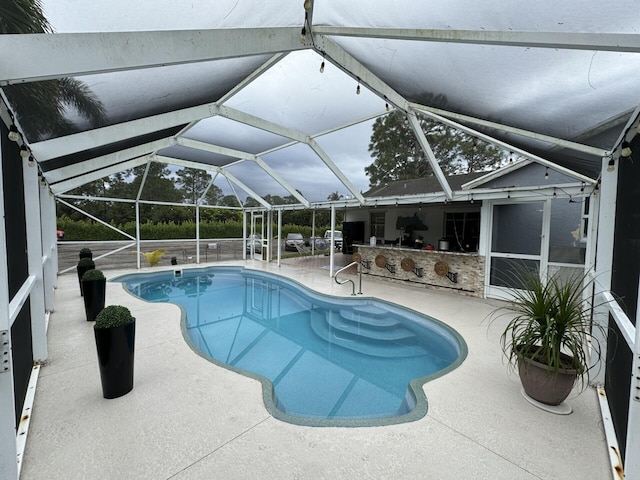 view of pool with a patio, a lanai, and an outdoor bar