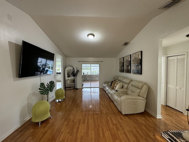 living room featuring hardwood / wood-style flooring, vaulted ceiling, and a textured ceiling