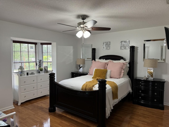 bedroom with a textured ceiling, dark wood-type flooring, and ceiling fan