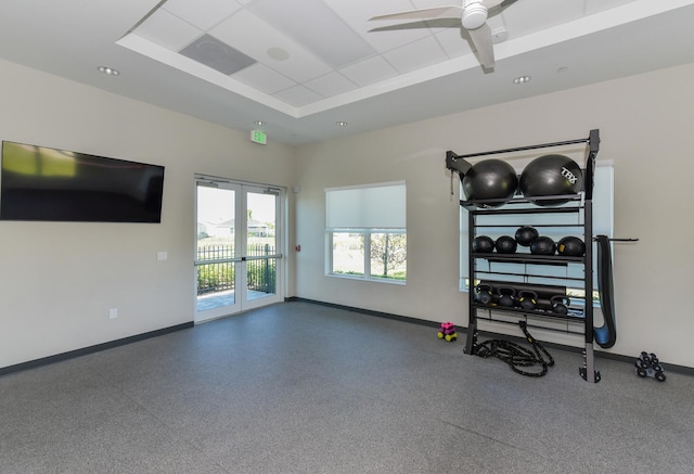 workout room with a tray ceiling, ceiling fan, and french doors