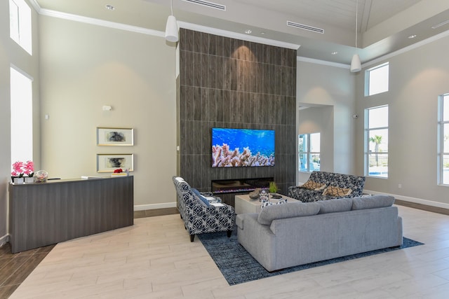 living room featuring a tile fireplace, a towering ceiling, and ornamental molding